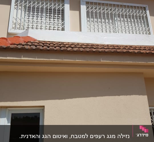 רעפים חומים על גג בית עם קיר לבן